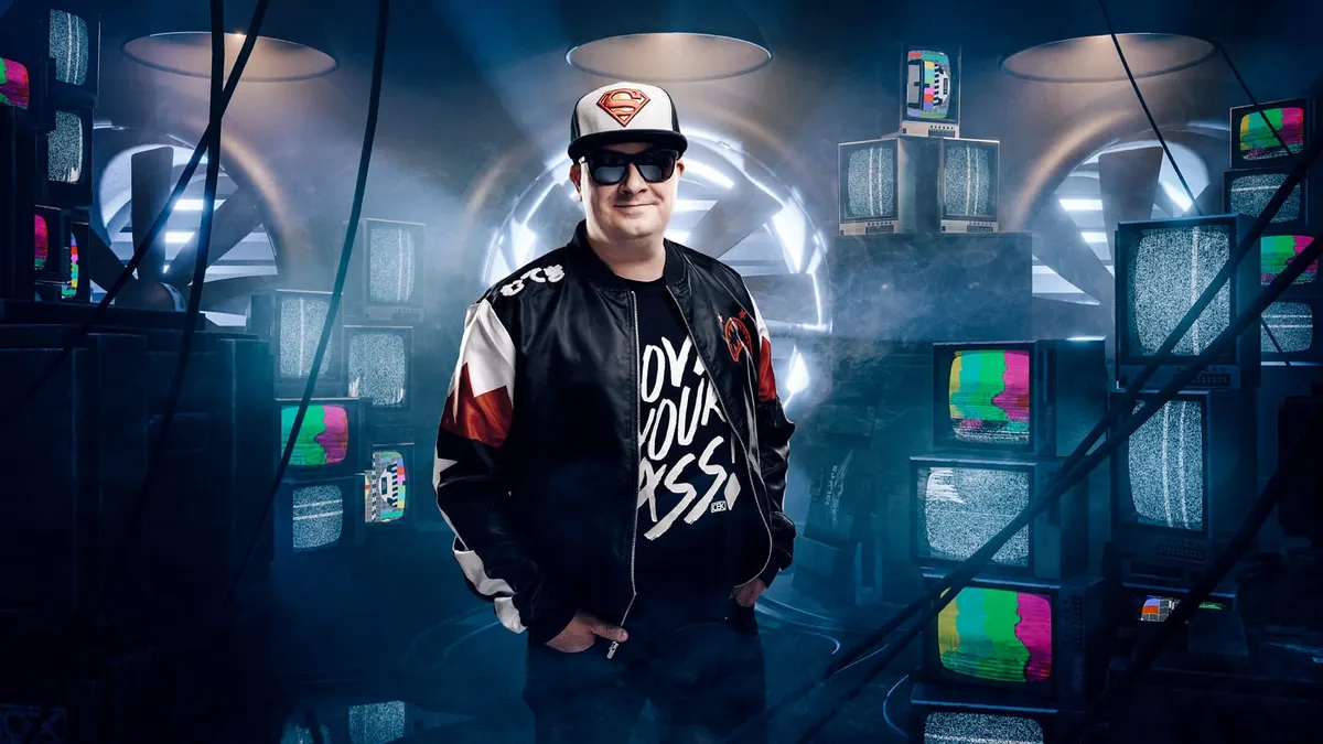 DJ Ice K aurinkolaseissa ja Superman-lippalakissa vanhojen televisioiden ympäröimänä